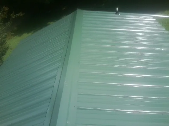 New green metal panels meeting at the ridge of a roof — Flat Roof Repair work by our crew in Seligman