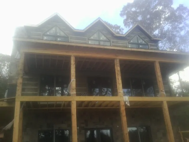 Dormers and porch framing on a large log home under construction — Roof Coating work by our crew in Seligman
