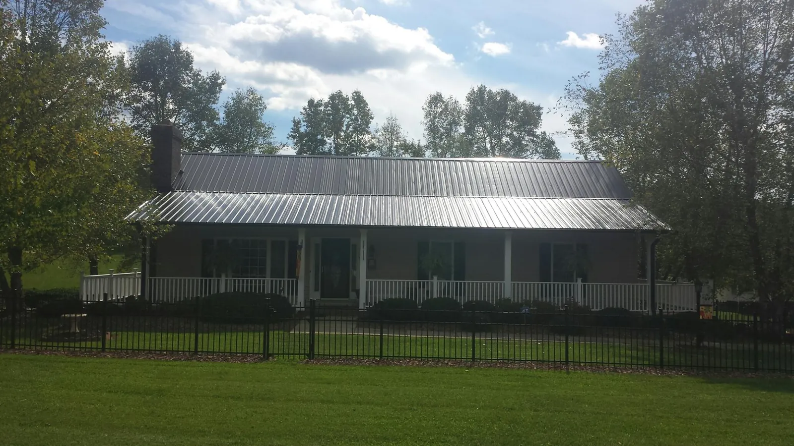 Gray metal roof on a brick ranch with a full width front porch — Gutter Guard Installation work by our crew in Seligman