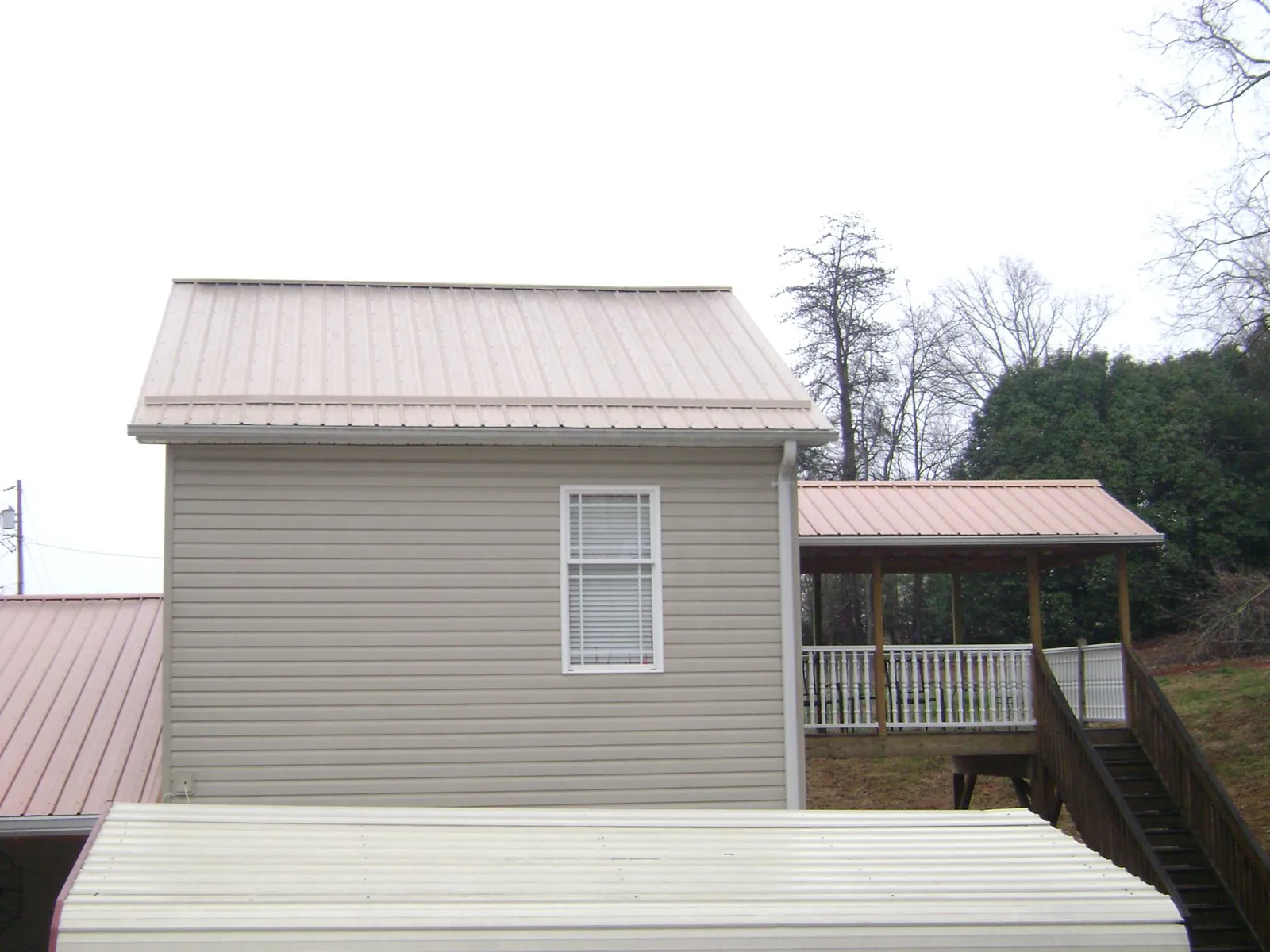 Tan metal roofs on a two story addition and attached porch, from a Roof Replacement job in Seligman