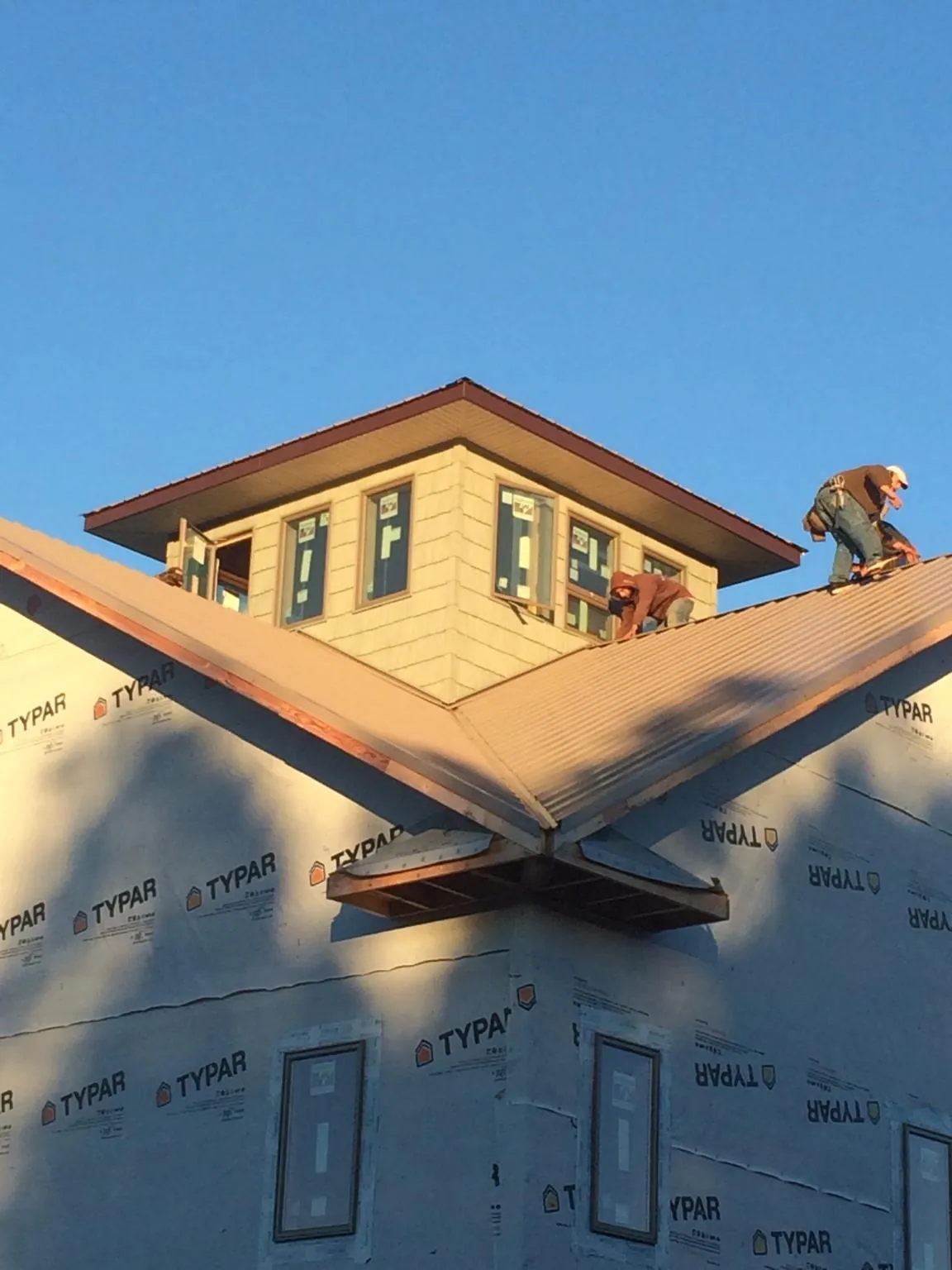 Roofers working around a rooftop cupola on a new metal roof at sunset — Roof Waterproofing in Seligman by Roofing Brothers